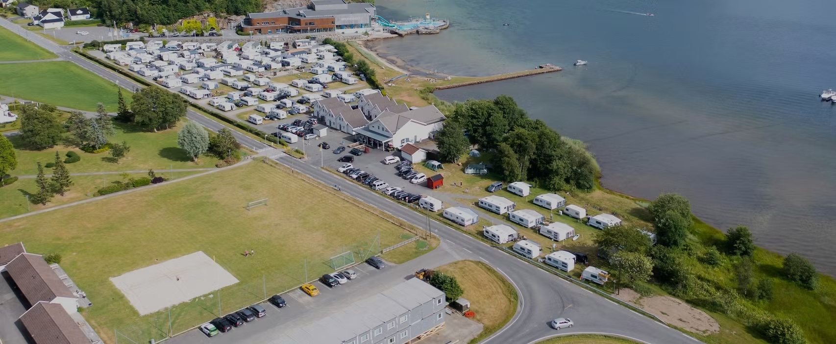 Flyfoto av campingplassen ved KVS-Lyngdal, med campingvogner langs fjorden